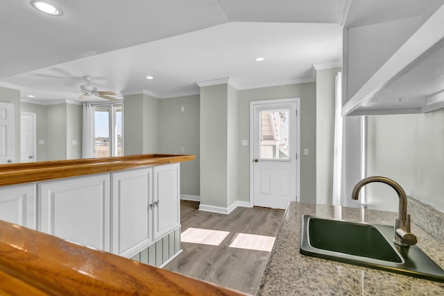 kitchen featuring ornamental molding, recessed lighting, dark wood-style floors, white cabinetry, and a sink