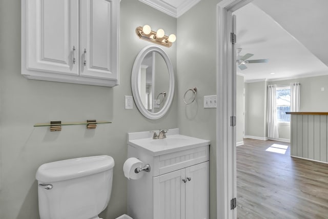 bathroom with baseboards, toilet, ornamental molding, wood finished floors, and vanity