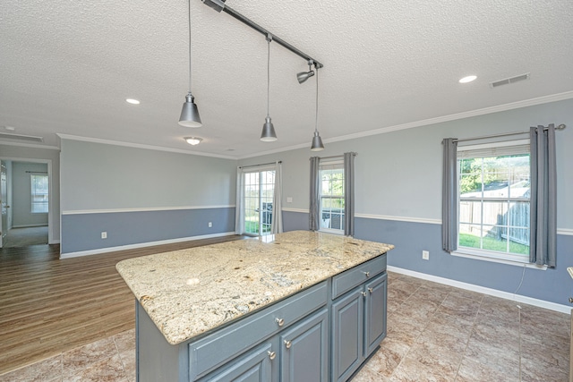 kitchen featuring light hardwood / wood-style flooring, a kitchen island, pendant lighting, and a textured ceiling