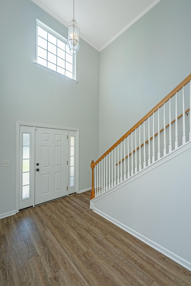 foyer featuring a wealth of natural light, crown molding, dark hardwood / wood-style floors, and an inviting chandelier