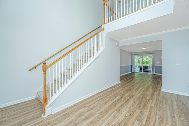 staircase with hardwood / wood-style flooring and ornamental molding