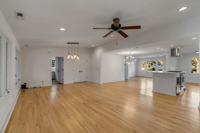 unfurnished living room featuring ceiling fan with notable chandelier and light hardwood / wood-style floors