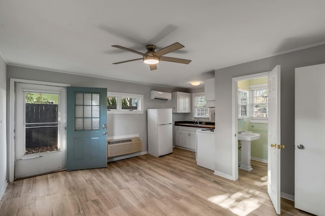 kitchen featuring white cabinetry, white appliances, light hardwood / wood-style flooring, and a wall unit AC