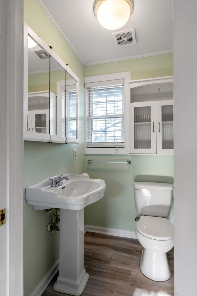 bathroom with hardwood / wood-style flooring, ornamental molding, and toilet