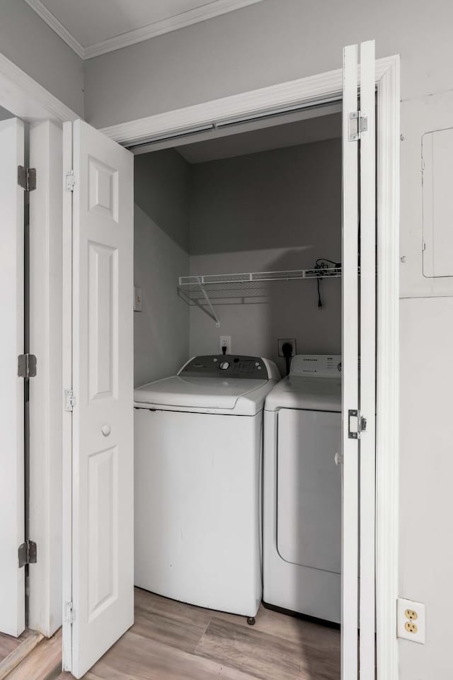 washroom with washing machine and clothes dryer, ornamental molding, and light hardwood / wood-style floors