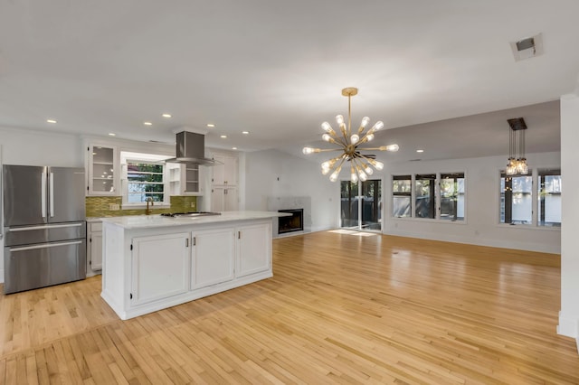 kitchen with island range hood, decorative light fixtures, a center island, stainless steel appliances, and white cabinets