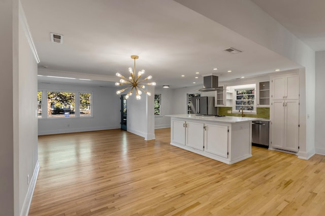 kitchen featuring a kitchen island, appliances with stainless steel finishes, white cabinets, and island exhaust hood