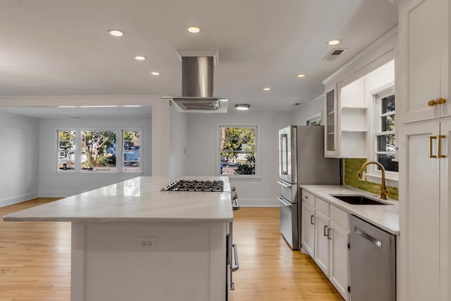 kitchen featuring stainless steel appliances, island exhaust hood, sink, and white cabinets