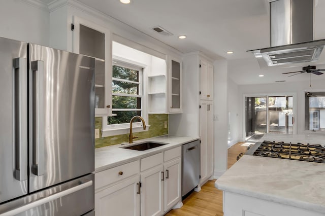 kitchen with sink, white cabinetry, light stone counters, appliances with stainless steel finishes, and exhaust hood