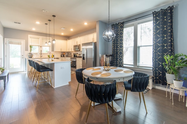 dining space with sink, a chandelier, dark hardwood / wood-style flooring, and a wealth of natural light