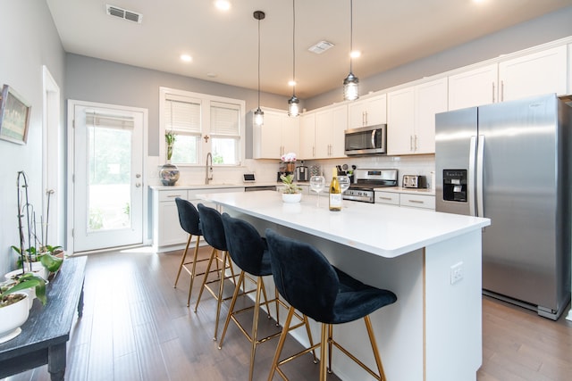 kitchen with white cabinetry, a center island, stainless steel appliances, and decorative light fixtures