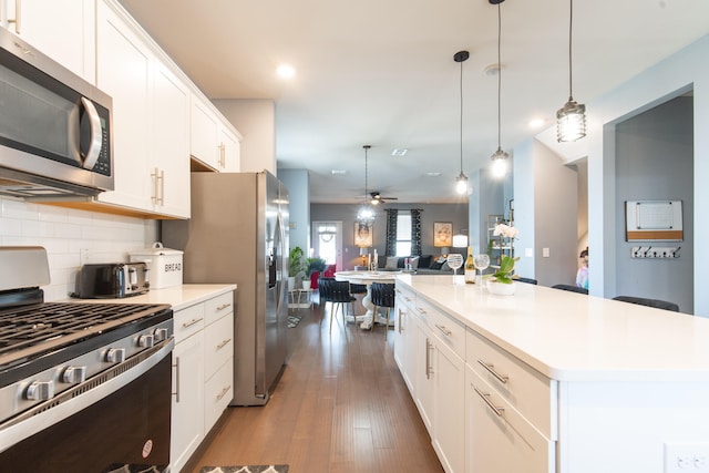 kitchen with white cabinetry, a kitchen island, appliances with stainless steel finishes, dark hardwood / wood-style flooring, and ceiling fan