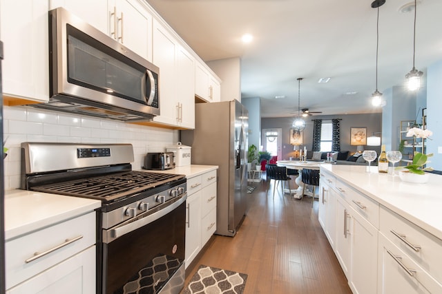 kitchen featuring white cabinetry, hanging light fixtures, stainless steel appliances, dark hardwood / wood-style flooring, and ceiling fan