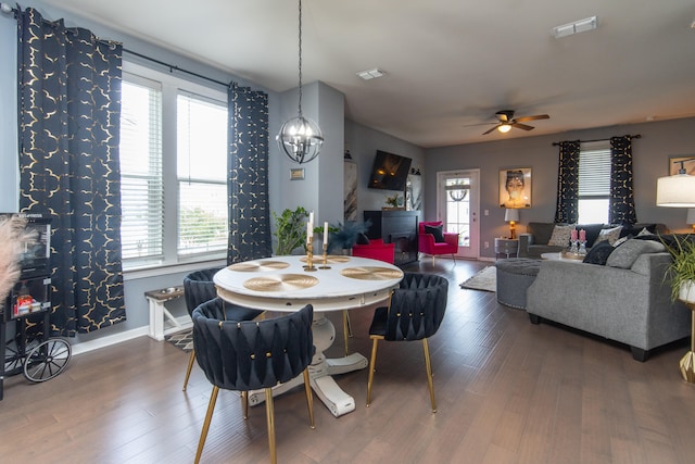 dining space featuring ceiling fan with notable chandelier, dark hardwood / wood-style floors, and a healthy amount of sunlight