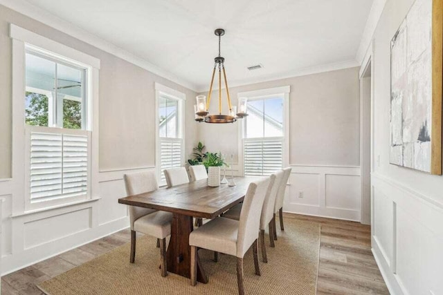 dining space featuring light hardwood / wood-style floors, a chandelier, plenty of natural light, and ornamental molding