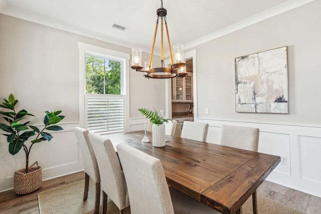 dining room with an inviting chandelier, hardwood / wood-style flooring, and crown molding