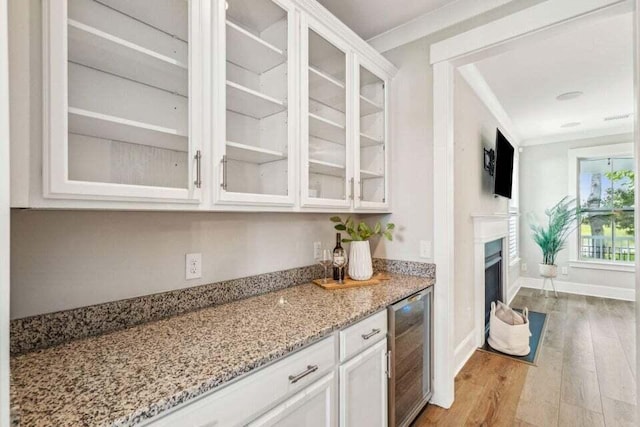 kitchen featuring white cabinetry, light wood-type flooring, ornamental molding, and beverage cooler