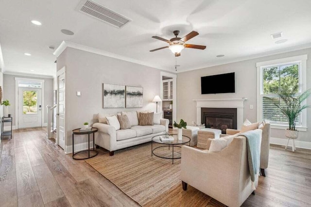 living room featuring ornamental molding, light hardwood / wood-style flooring, a healthy amount of sunlight, and ceiling fan