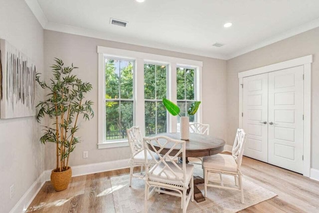 dining space featuring light wood-type flooring, ornamental molding, and plenty of natural light