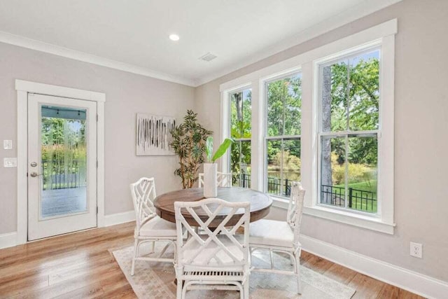 dining room with light wood-type flooring and ornamental molding