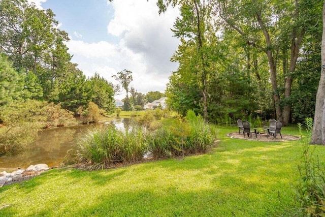 view of yard featuring a patio area, a water view, and an outdoor fire pit