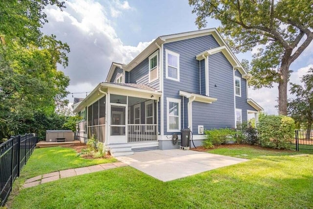 rear view of property with a lawn, a sunroom, a patio, and a hot tub