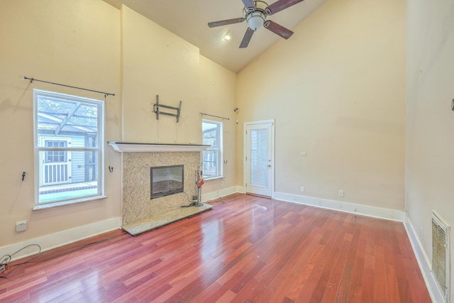 unfurnished living room featuring a high end fireplace, ceiling fan, hardwood / wood-style floors, and high vaulted ceiling