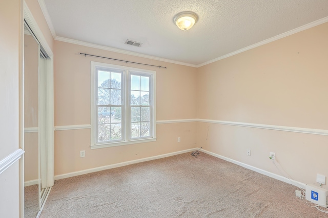 empty room with carpet, a textured ceiling, and crown molding