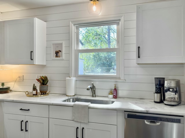 kitchen with stainless steel dishwasher, a sink, and white cabinets