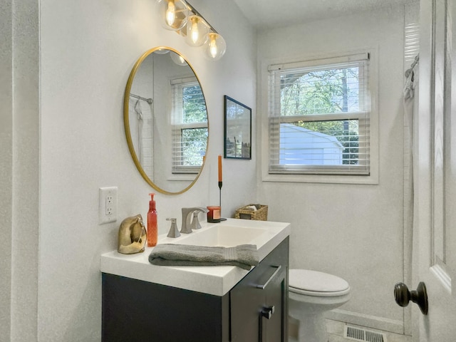 bathroom with toilet, visible vents, a wealth of natural light, and vanity