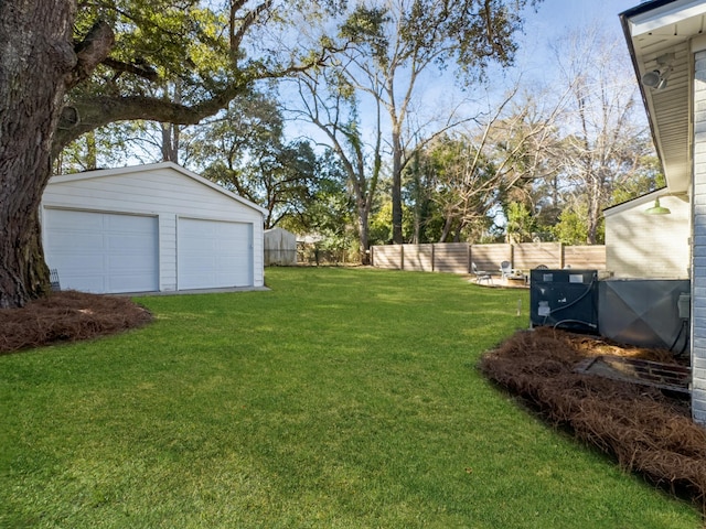 view of yard featuring a fenced backyard, a detached garage, and an outdoor structure