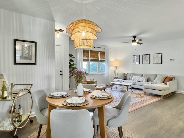 dining space featuring baseboards, wood finished floors, and ceiling fan with notable chandelier