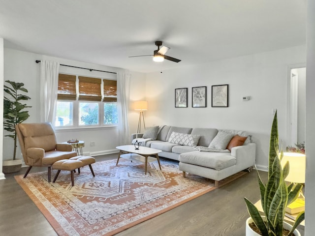 living room featuring wood finished floors, a ceiling fan, and baseboards