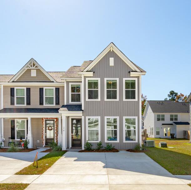 view of front facade with a front lawn, board and batten siding, and cooling unit