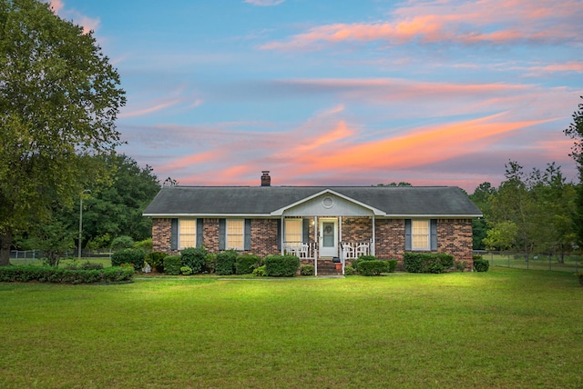 ranch-style house featuring a porch and a lawn