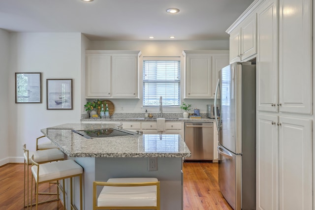 2028 Prospect Hill Dr, Mount Pleasant, SC 29464 - kitchen featuring appliances with stainless steel finishes, a sink, white cabinetry, a breakfast bar area, and light wood-style floors