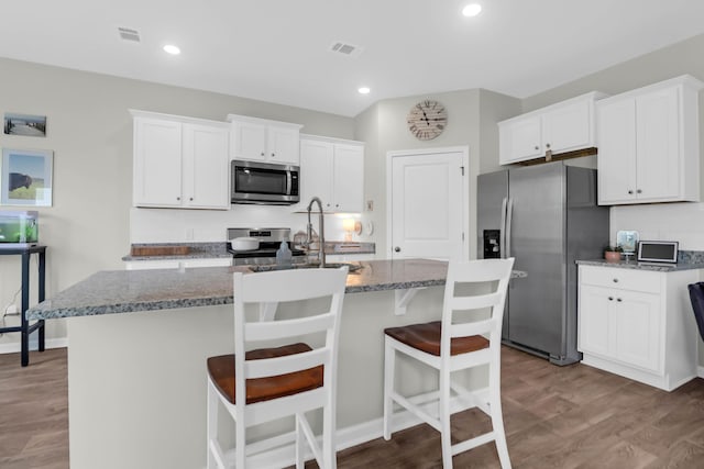 725 Pepperbush St, Charleston, SC 29414 - kitchen with appliances with stainless steel finishes, a kitchen island with sink, white cabinets, wood finished floors, and recessed lighting