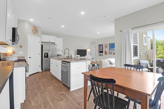 725 Pepperbush St, Charleston, SC 29414 - kitchen featuring appliances with stainless steel finishes, a sink, light wood-style floors, a kitchen island with sink, and white cabinetry