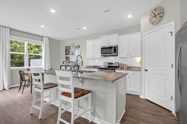 725 Pepperbush St, Charleston, SC 29414 - kitchen featuring appliances with stainless steel finishes, a sink, dark wood finished floors, a kitchen island with sink, and light stone counters