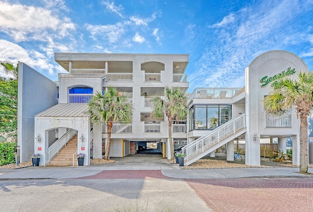 view of building exterior with a carport, decorative driveway, and stairway