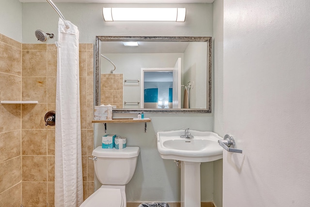 full bath featuring toilet, a tile shower, and a sink