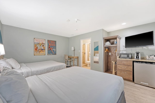 bedroom with connected bathroom, refrigerator, a dry bar, and light wood-style flooring