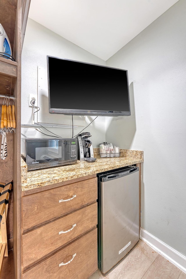 details featuring baseboards, wood finished floors, and refrigerator