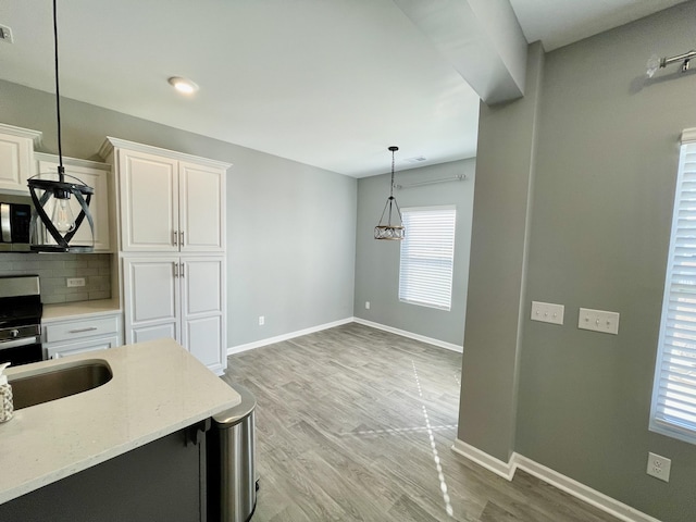 kitchen with hanging light fixtures, white cabinetry, tasteful backsplash, and range