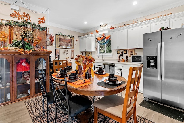 dining space with sink, light hardwood / wood-style flooring, and ornamental molding