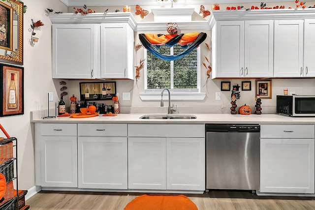 kitchen with white cabinetry, sink, stainless steel dishwasher, and light hardwood / wood-style floors