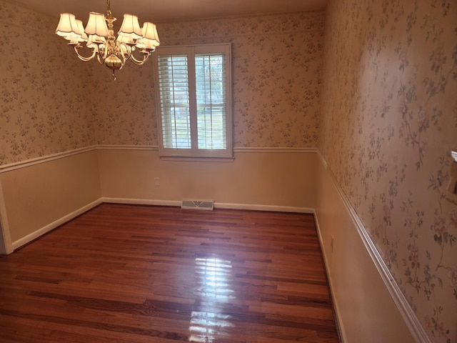 unfurnished room with a notable chandelier and dark hardwood / wood-style floors