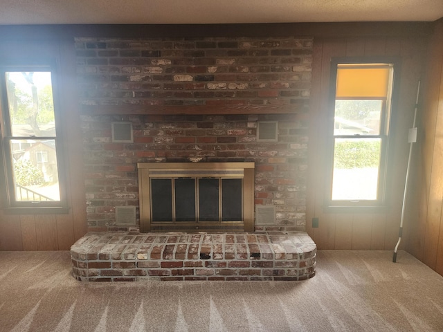 details with a fireplace, a textured ceiling, wooden walls, and carpet