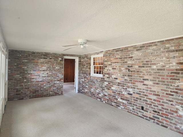 carpeted spare room featuring ceiling fan, brick wall, and a textured ceiling