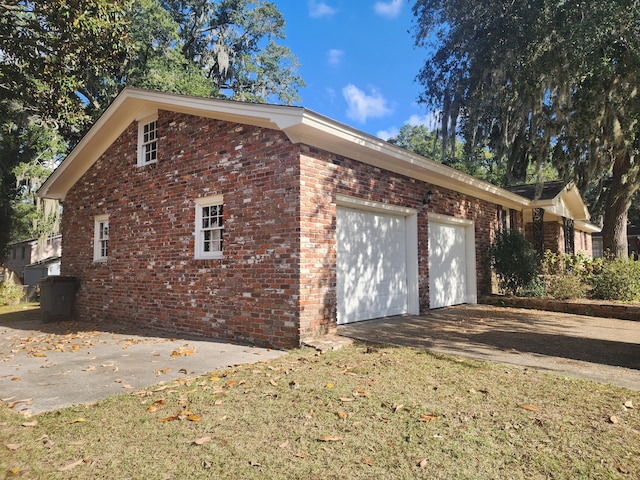 view of side of home featuring a garage and a lawn